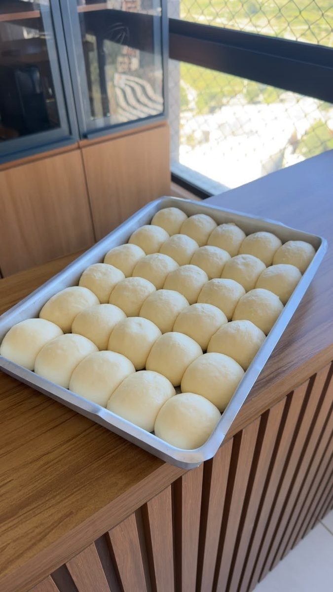 Bandeja cheia de pãezinhos boleados e crescidos, produção em lote